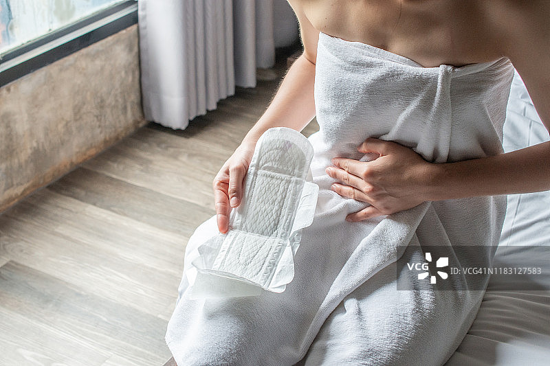 女人拿着卫生巾或月经垫，准备使用。女性在月经期间使用，以避免弄脏衣服图片素材