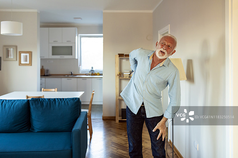 在起居室背痛的年长男人图片素材