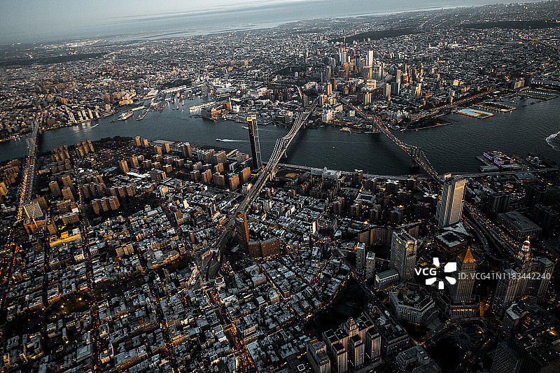 纽约布鲁克林大桥、曼哈顿大桥和威廉斯堡大桥的金色时段航拍，从曼哈顿下城岛上方的直升机拍摄图片素材