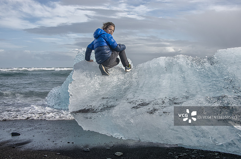 男孩在冰岛钻石海滩攀爬冰块图片素材