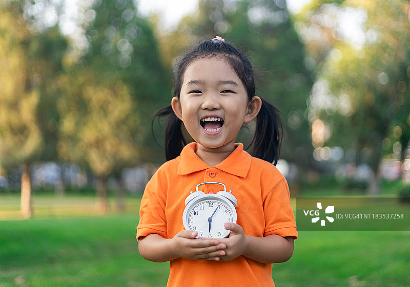 可爱的小女孩拿着一个时钟图片素材