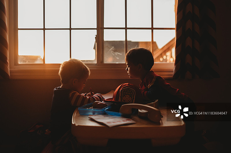 幼儿异卵双胞胎在家里的野餐桌上玩耍和绘画图片素材