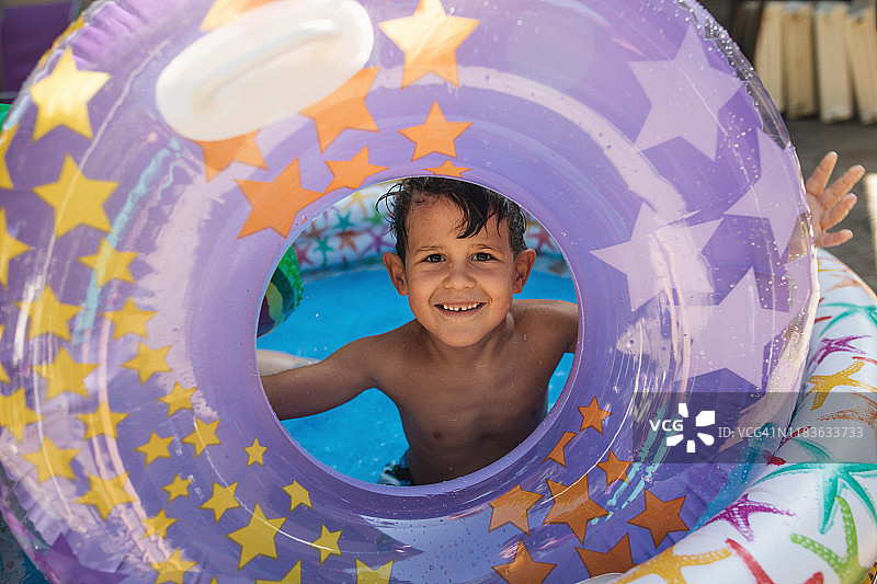 男孩透过充气游泳圈看镜头图片素材