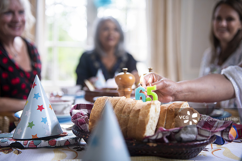 一群女性举办纯素生日午餐派对：点燃蜡烛图片素材