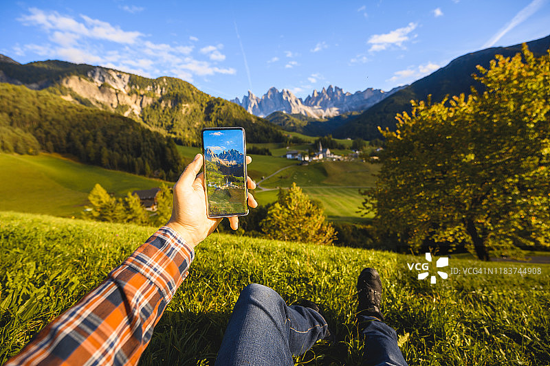 男人坐在草地上拍摄意大利多洛米蒂山脉的个人视角图片素材