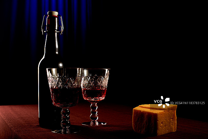 桌子上放着水晶玻璃杯的酒瓶蓝色背景图片素材