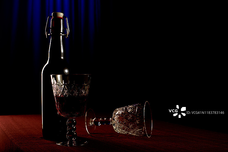 桌子上放着水晶玻璃杯的酒瓶蓝色背景图片素材