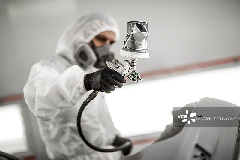 油漆技师在车身车间的喷漆室用喷枪为汽车保险杠喷漆图片素材