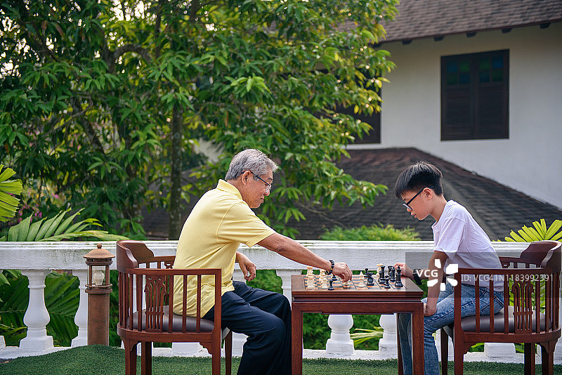 爷爷在花园里和孙子下棋图片素材