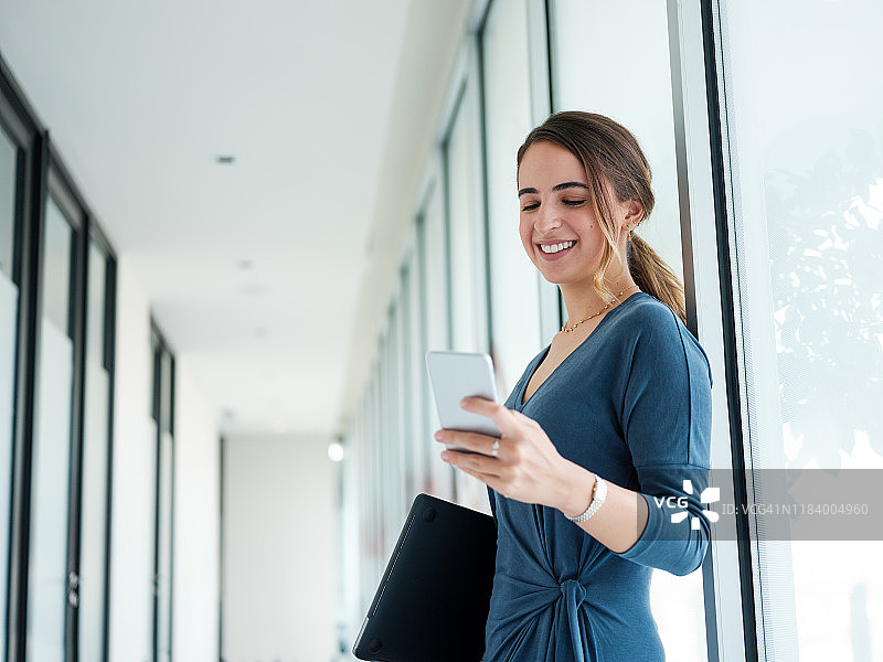 年轻女商人用手机发短信，面带微笑图片素材