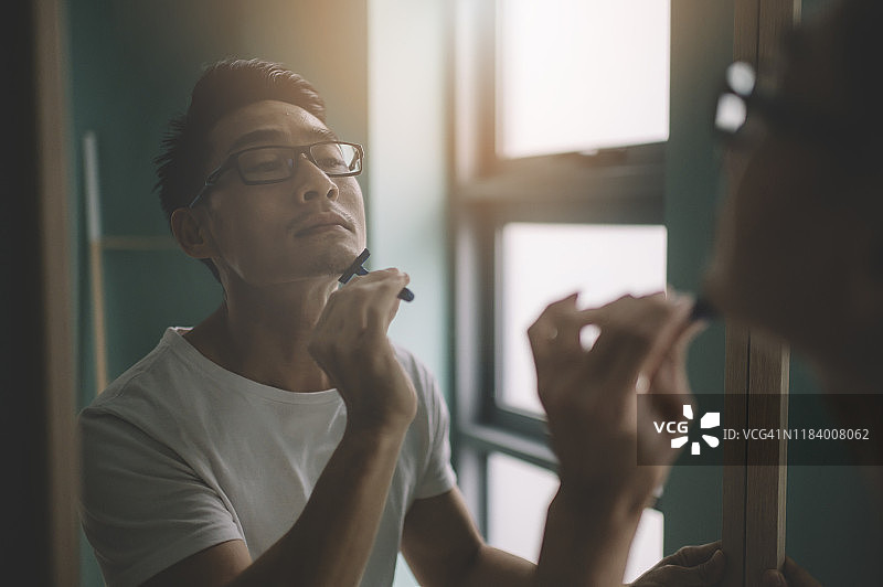 早上刮胡子准备上班的亚洲男人图片素材