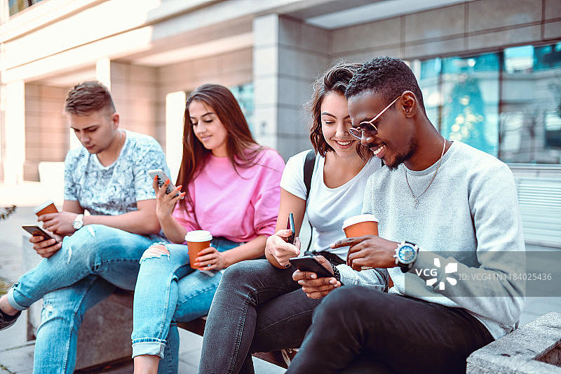朋友们享用咖啡玩智能手机图片素材