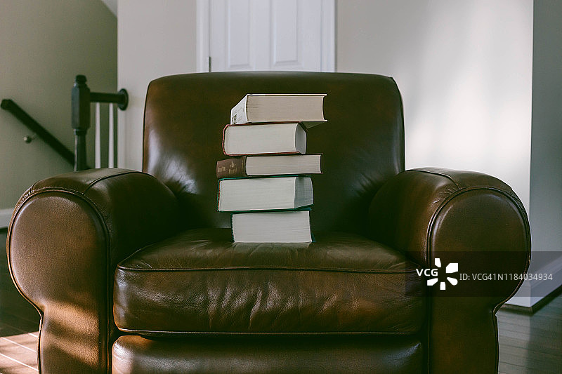 皮质扶手椅上的书籍堆叠图片素材