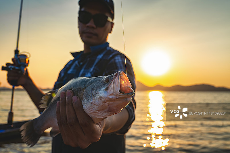 男子在湖上钓鱼并拿着鱼图片素材