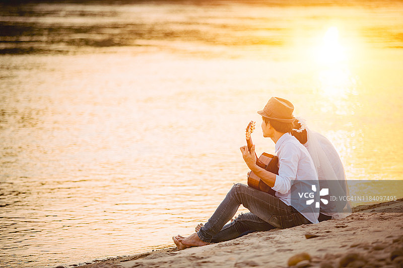 蜜月情侣在日落海滩上唱歌弹吉他图片素材