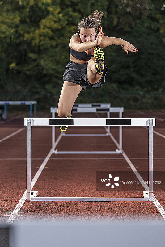 女运动员在赛道上跨越栏架图片素材