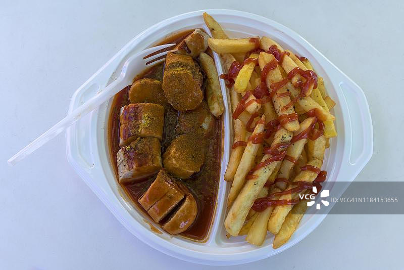 德国快餐：咖喱香肠配炸薯条和塑料叉图片素材