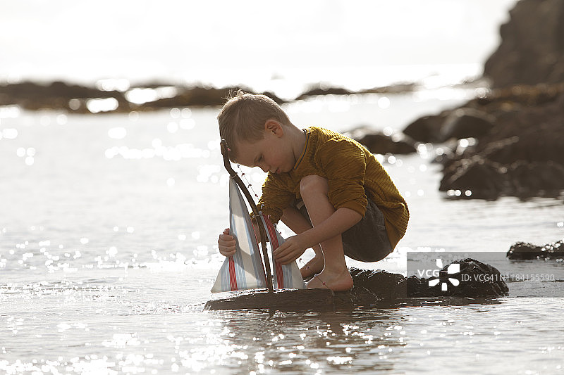 在海里玩玩具船的男孩图片素材