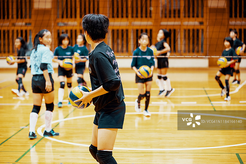 小女孩在学校体育馆打排球团队训练图片素材