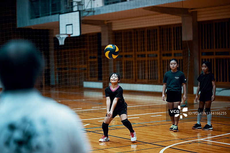 小女孩在学校体育馆打排球团队训练图片素材