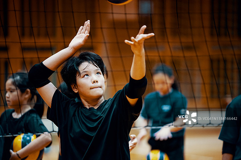 在学校体育馆团队排球训练中扣球的年轻女孩图片素材