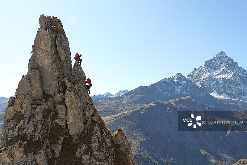 登山向导引导年轻女性攀登岩石顶峰图片素材
