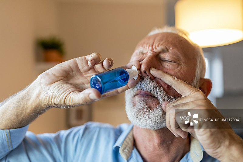 使用鼻腔喷雾剂的年长的男人图片素材
