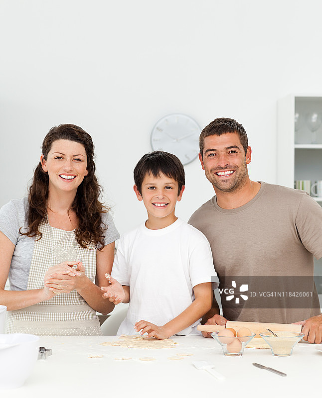 在厨房里和父母在一起的可爱男孩图片素材