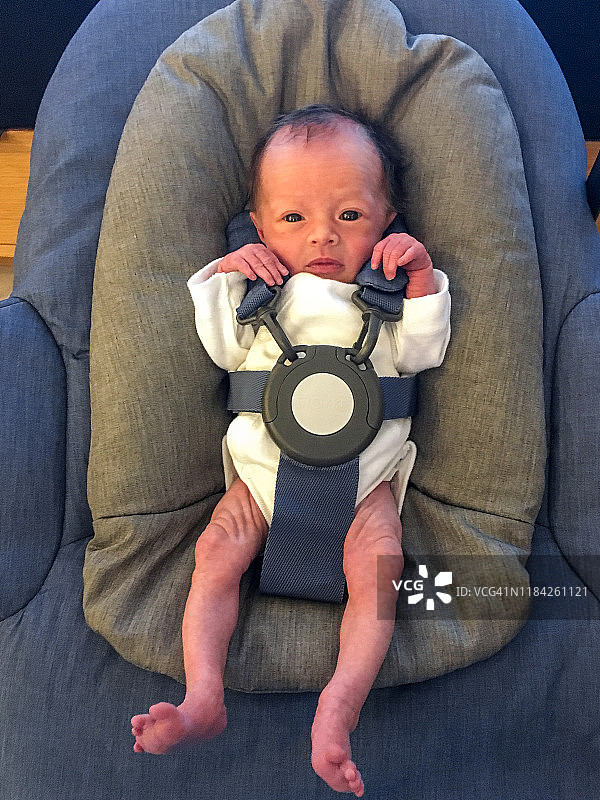 新生婴儿绑在婴儿座椅上图片素材