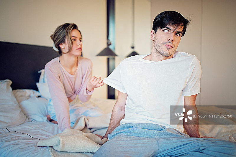 女孩在床上寻求闷闷不乐的伴侣的关注图片素材