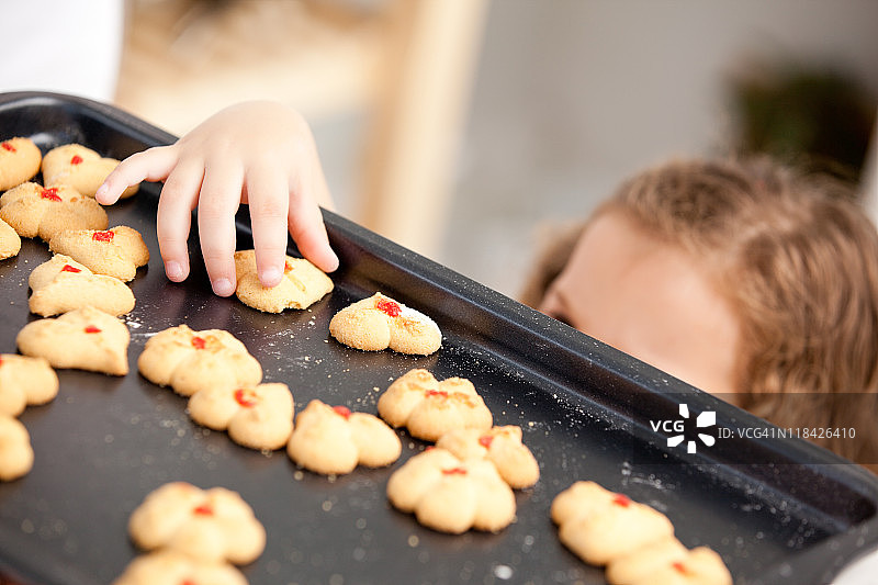 小女孩在妈妈身后偷拿饼干图片素材