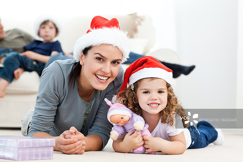 快乐的母亲和女儿在圣诞节躺在地板上图片素材