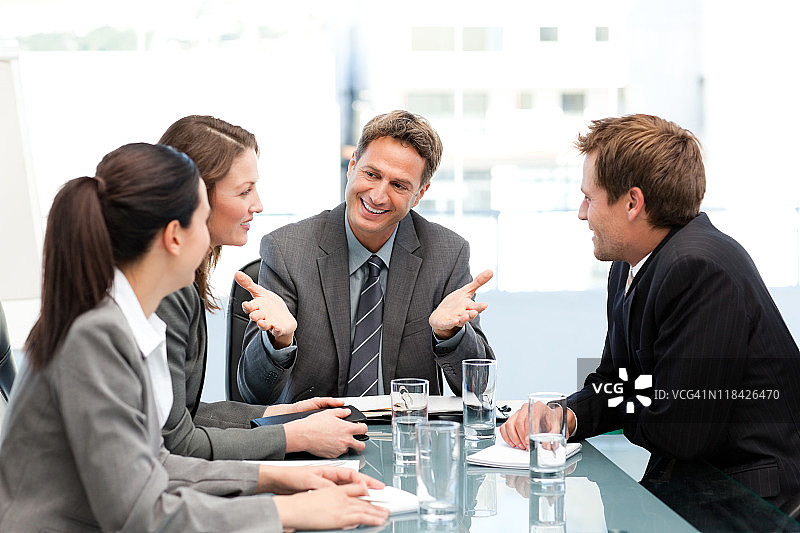 快乐的经理在桌旁与团队交谈图片素材