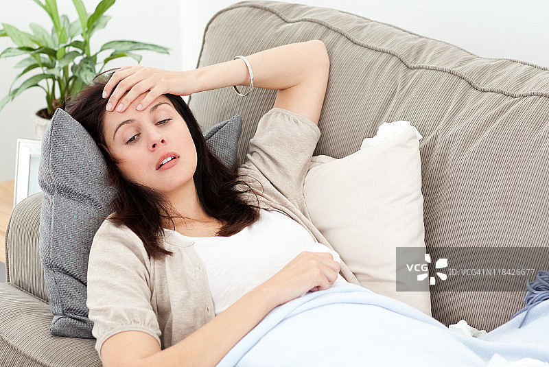 身体不适的女子在沙发上休息并测量体温图片素材