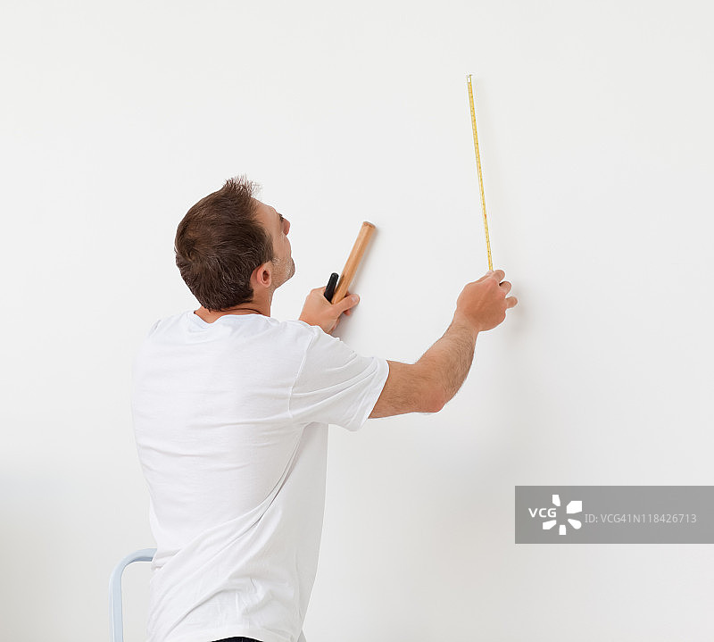 一位男士拿着尺子和工具看着墙壁图片素材