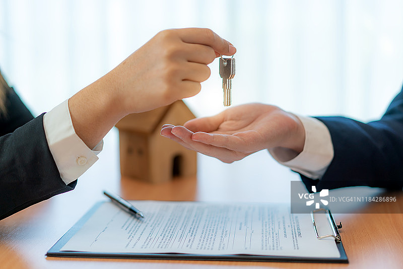 女房地产经纪人交出新房钥匙，在签署租赁合同后将房屋钥匙交给男人，涉及抵押贷款和房屋保险。图片素材