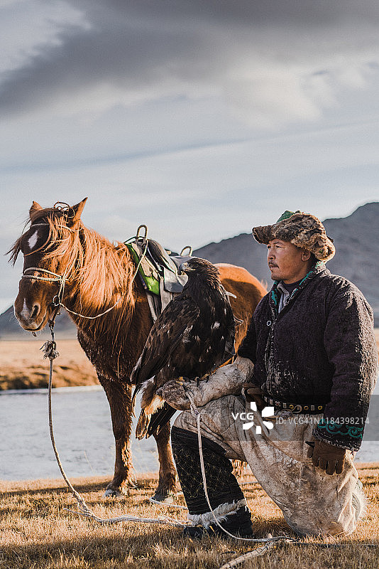 蒙古，河流附近的猎鹰人和马匹图片素材