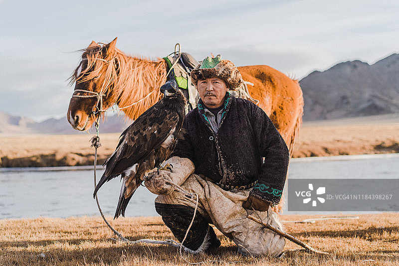 蒙古，河流附近的猎鹰人和马匹图片素材