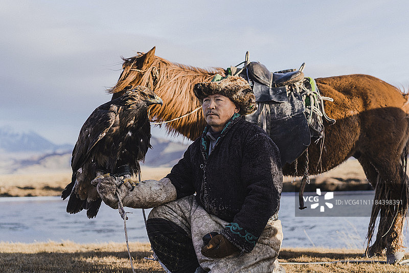 蒙古，河流附近的猎鹰人和马匹图片素材