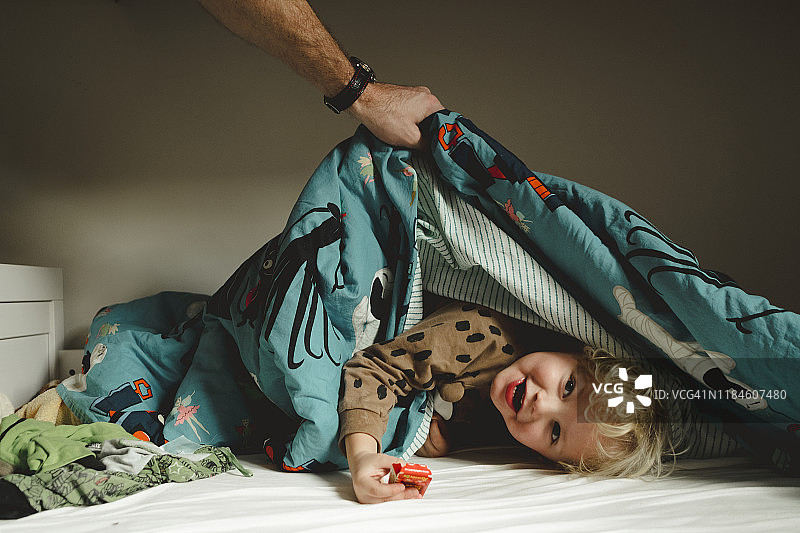 微笑的男孩在被子下图片素材