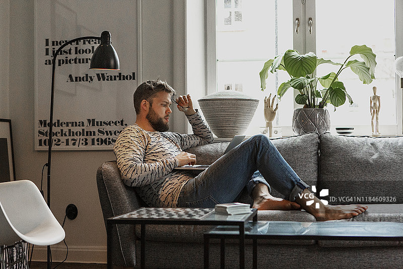 在沙发上使用笔记本电脑的男人图片素材