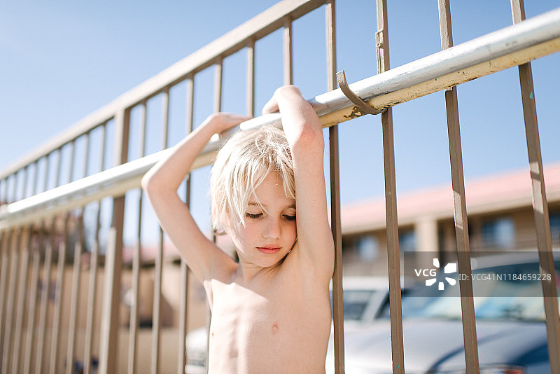 在美国内华达州拉斯维加斯酒店泳池边扶着栏杆的闭着眼睛的金发男孩图片素材