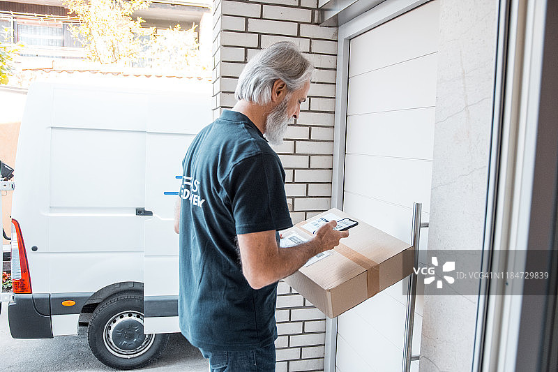 年长的邮政工作人员在门口拿着包裹等待图片素材