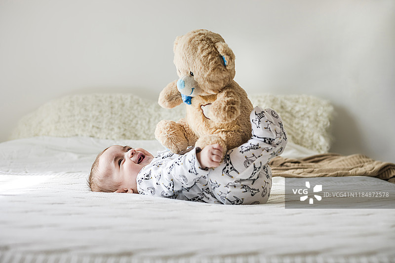 男婴在床上玩泰迪熊图片素材