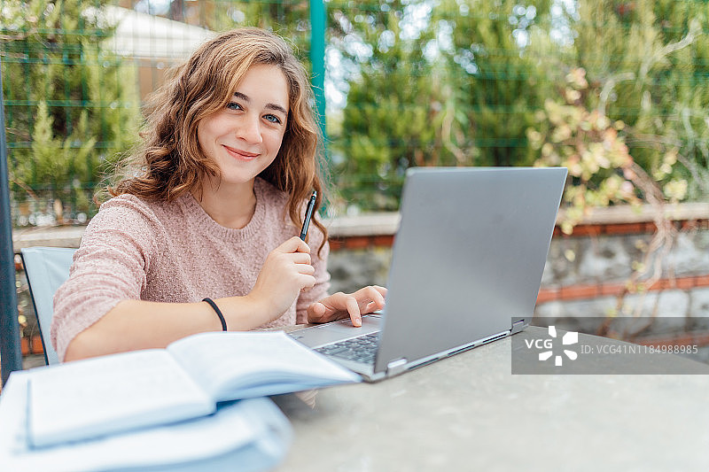 女孩坐在咖啡馆里，用电脑写笔记图片素材