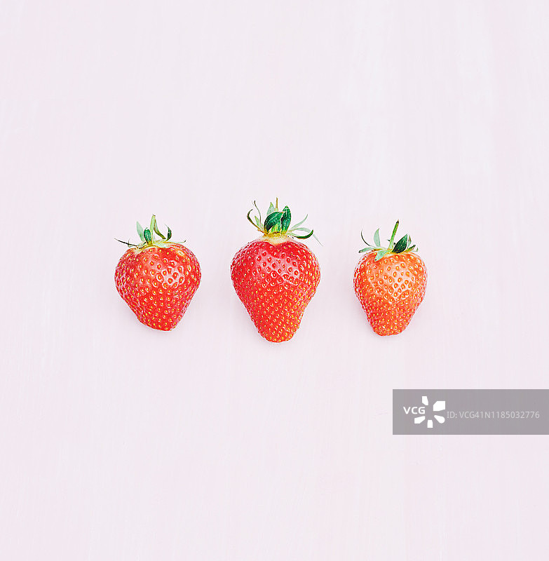 粉色背景上的三颗草莓图片素材