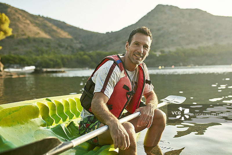 放松的西班牙男子皮划艇运动员，桨放在膝盖上图片素材