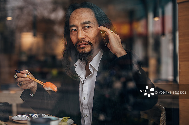 男人吃寿司并打电话图片素材