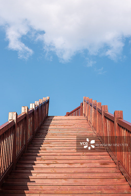 蓝色天空和白色云朵下的木制楼梯图片素材