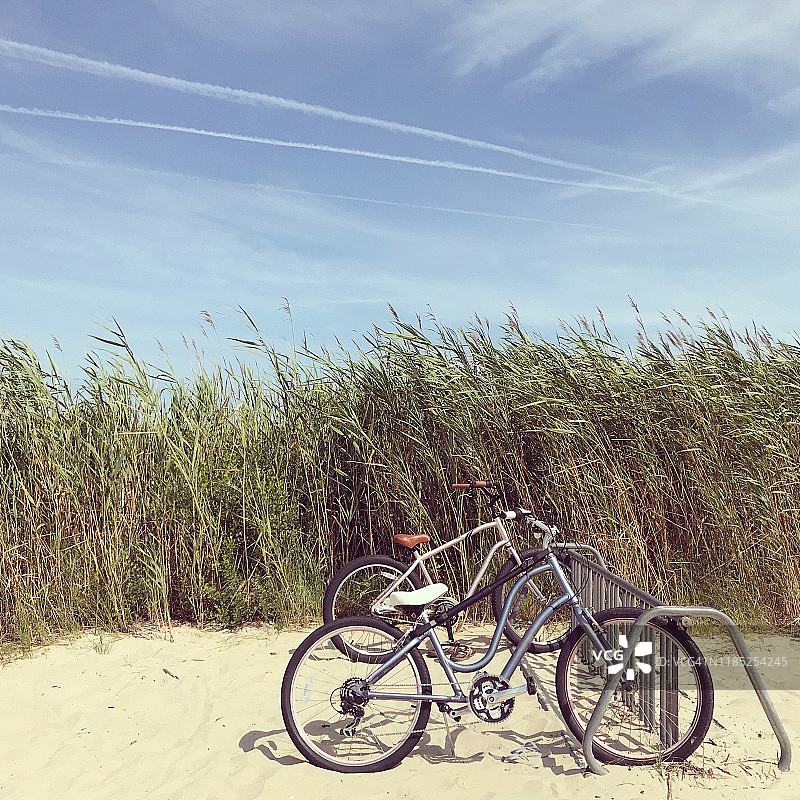 海滩边的自行车与远处的风中摇曳的草图片素材